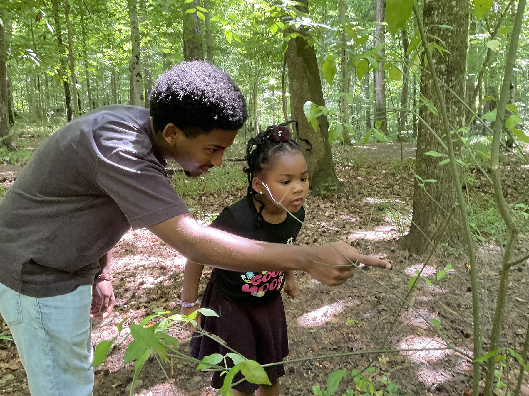 "I spy a tiny spider!" Assistant Teacher Thomas and a child explore Frazer Forest together.