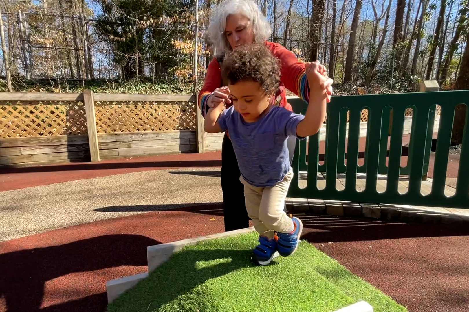 Khalil is building strength and learning to climb stairs, with just a little support from his therapist.