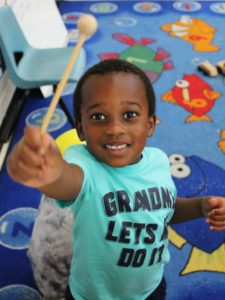 Little boy holding a drum mallet toward camera