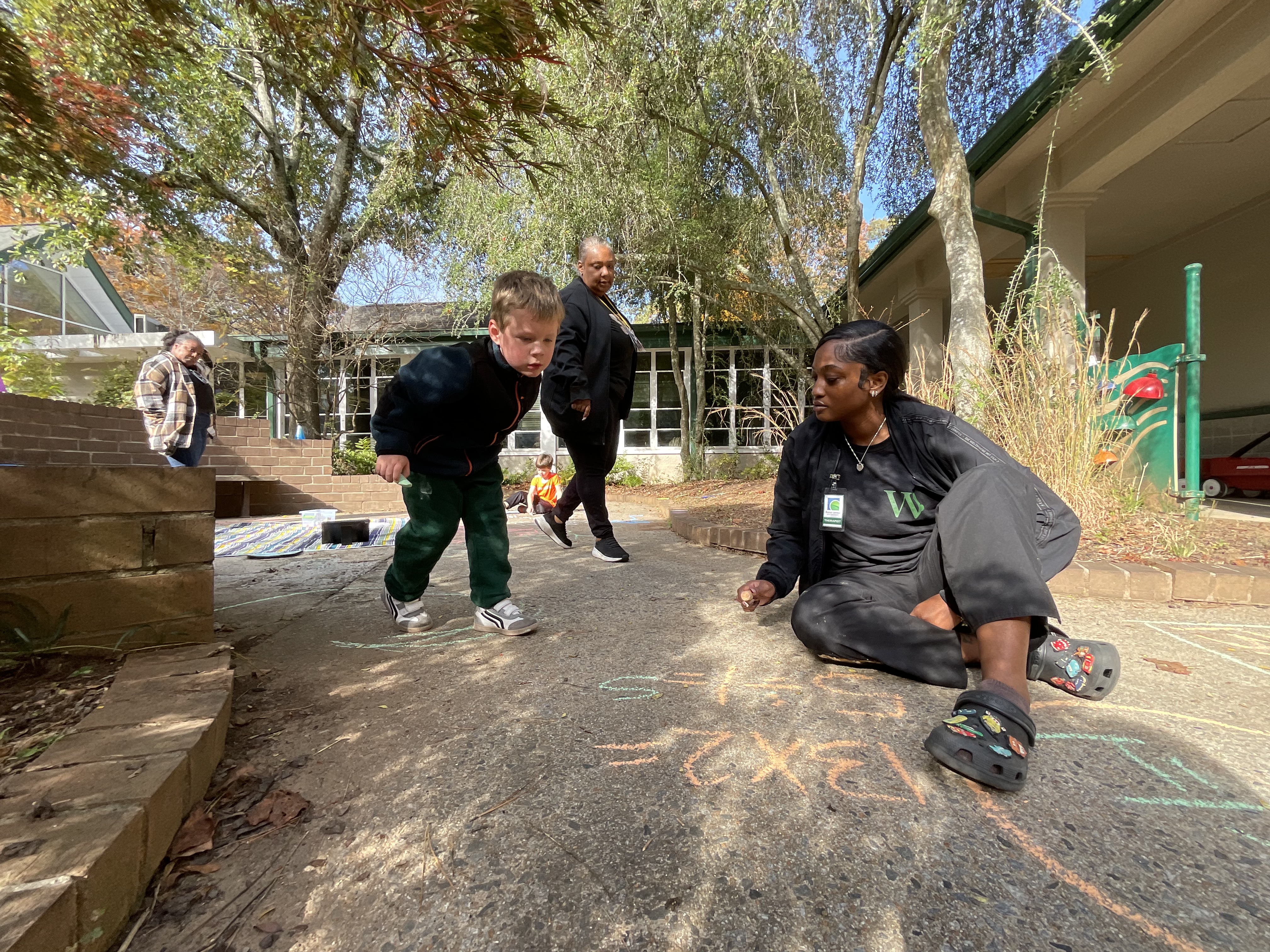 Leon solves math problems posed by his therapist, Carteria, while his teacher, Ms Flowers, looks on.