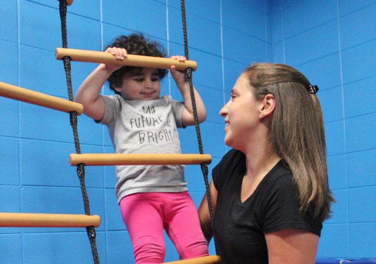 Therapist with little girl on play ladder